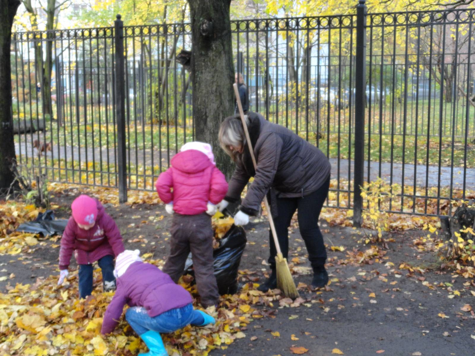 Дети убирают листву в саду